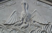 A relief depicting a mother pelican bleeding to feed her chicks.